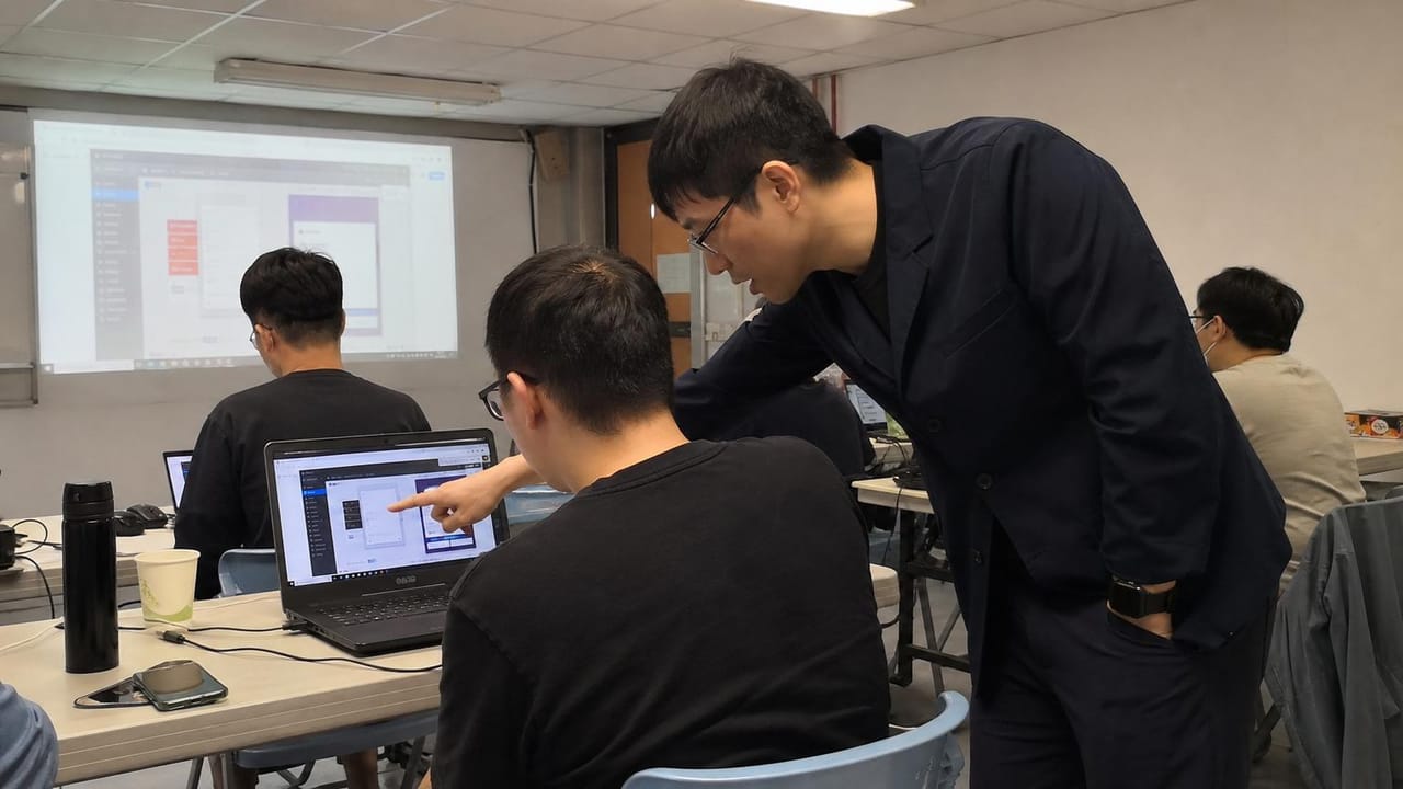 老師在普通教室裡貼近學員螢幕逐段除錯